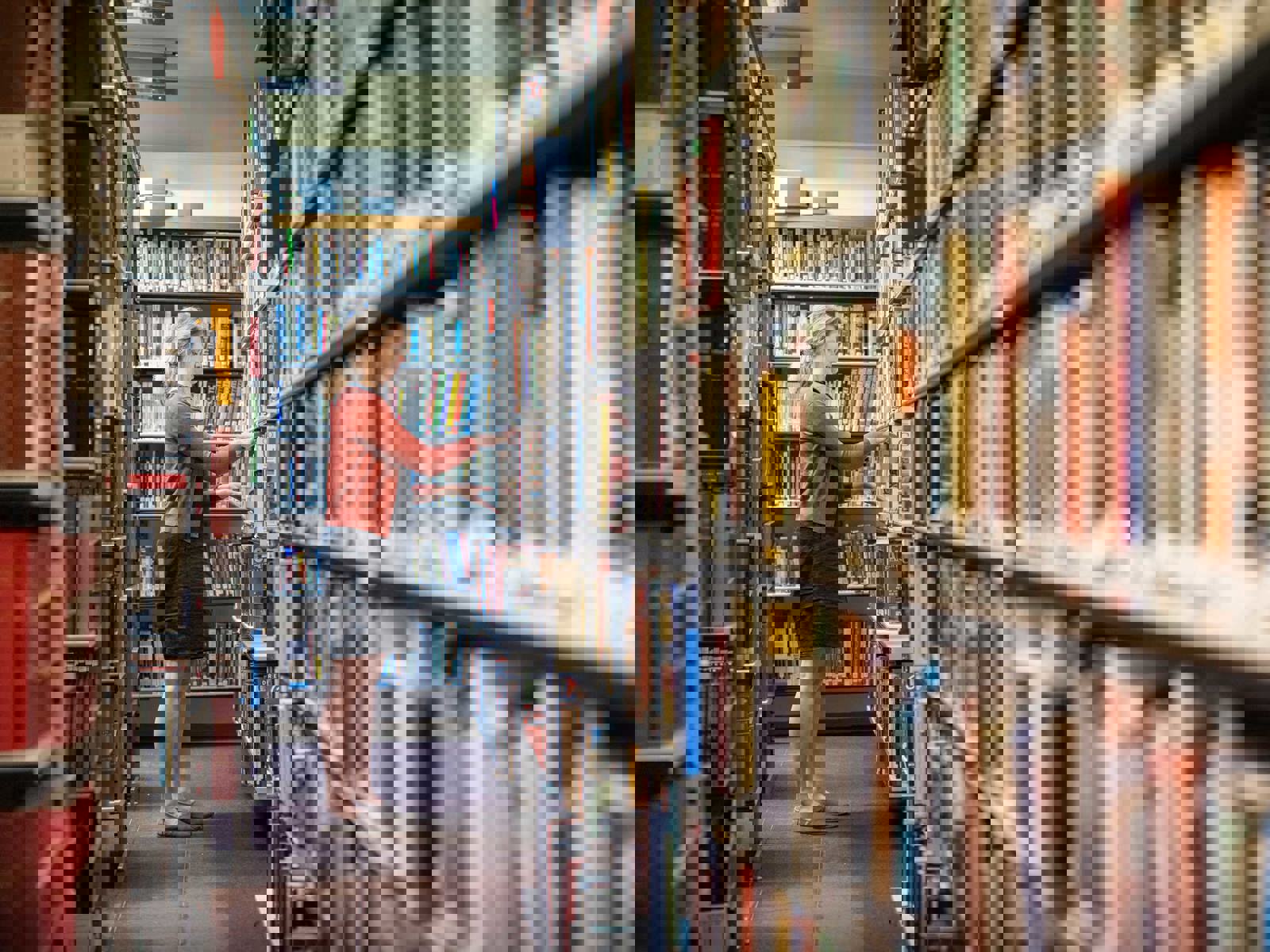 female member of staff taking books of library shelving